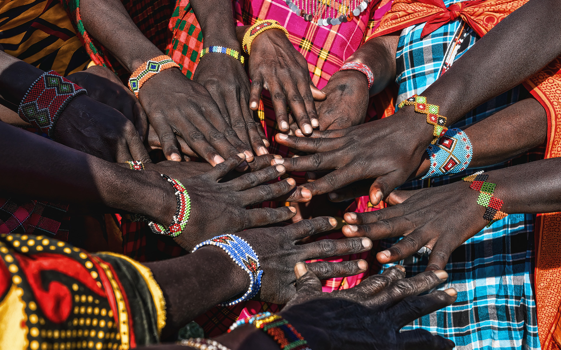 Hands of Maasai Mara tribe people putting together showing their bracelet and colorful clothing at Maasai Mara tribe village near Maasai Mara National reserve Kenya